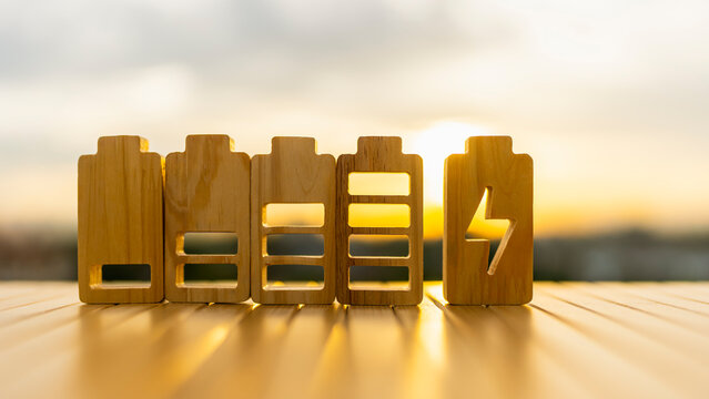 Battery wooden blocks showing charge level with lightning bolt icon at sunset for renewable energy, sustainability infrastructure, technology power and carbon neutral business concept.