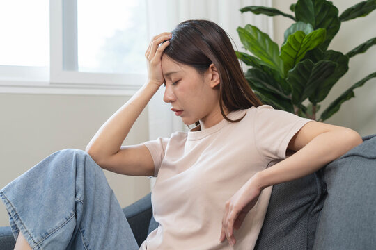Asians female in stressed expression sitting on the sofa in the house.