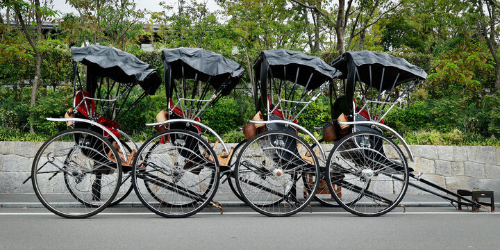 Row of four traditional Japanese rickshaws jinrikisha parked on street, Kyoto, Japan