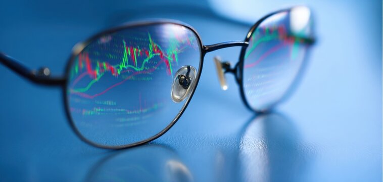 The glasses reflecting stock market candlestick charts on a blue surface