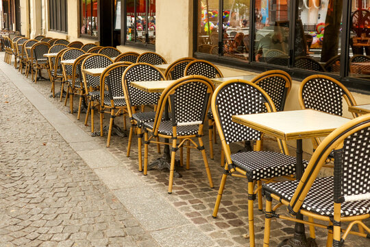 Empty street cafe tables and chairs in a row along a parisian sidewalk, representing travel and european culture