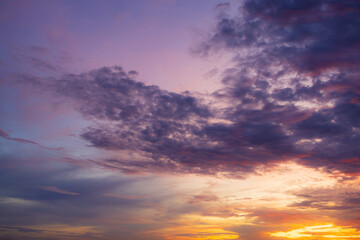 Fototapeta premium Dramatic Sunset Sky with Vibrant Twilight Clouds,Beautiful twilight sky during sunset featuring a dramatic blend of deep blue and purple clouds illuminated with vibrant orange, pink, and yellow hues.