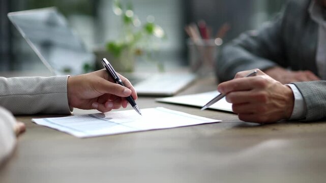 Two hands hover over signed papers