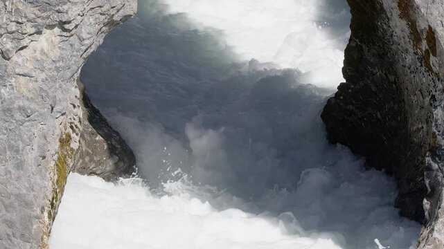 Foaming whitewater roils through narrow gap in bedrock riverbed gorge