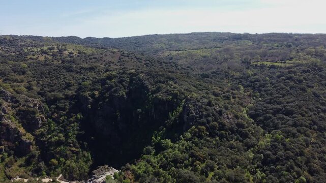 Impressive 4K aerial drone shot advancing slowly over rolling hills covered in lush green vegetation. Showcasing pure nature and flora diversity with holm oaks, cork oaks, and vibrant grass in Salaman