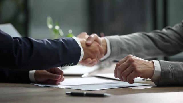 Two professionals shake hands over documents