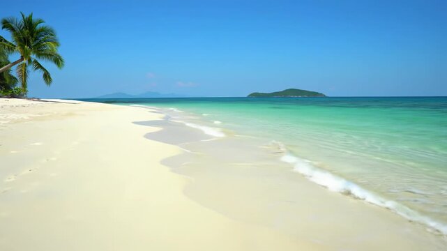 An establishing wide video captures a pristine white sand beach with gentle turquoise ocean waves under a vast cerulean sky, distant landforms. Tranquil tropical beach paradise