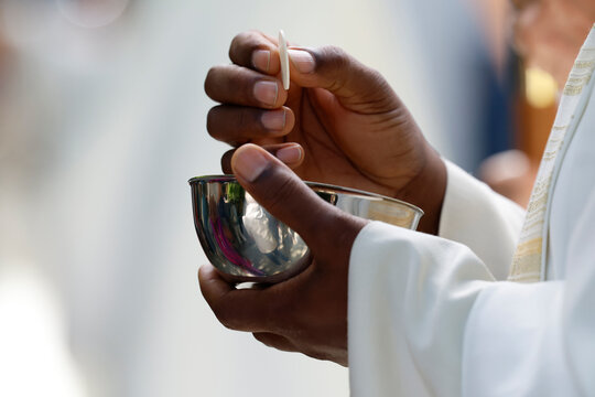 A priest holds a host above a ciborium during Mass. The Eucharist is a central sacrament of Christianity.