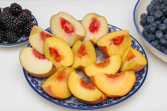 Juicy, ripe peaches and nectarines cut into pieces lying on a plate