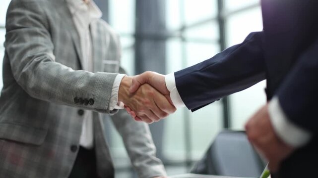 Two professionals shake hands in a modern office