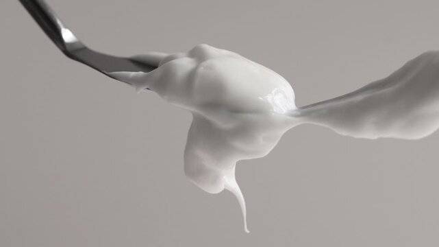 Two spatulas with a dense cosmetic texture of white cream, soap, shampoo close-up on a beige background.