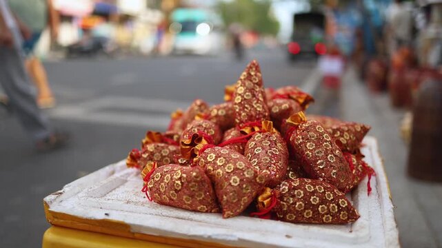 Traditional Vietnamese Tet lucky salt bags for sale on a street. Close-up of festive red and golden brocade pouches on a market display box before Lunar New Year celebration.
