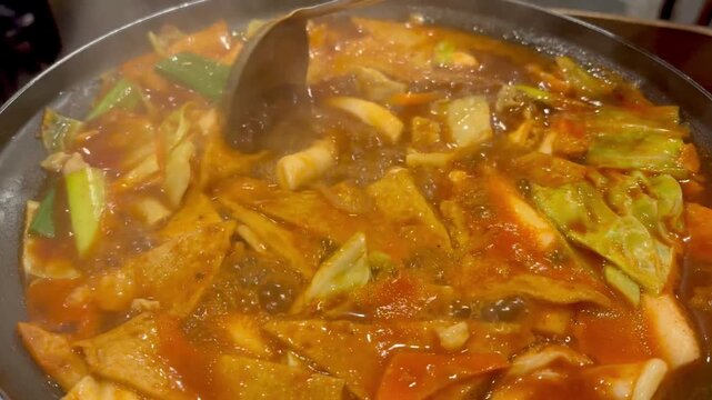 Close-up of bubbling spicy Tteokbokki, traditional Korean stir-fried rice cakes cooking in a pot