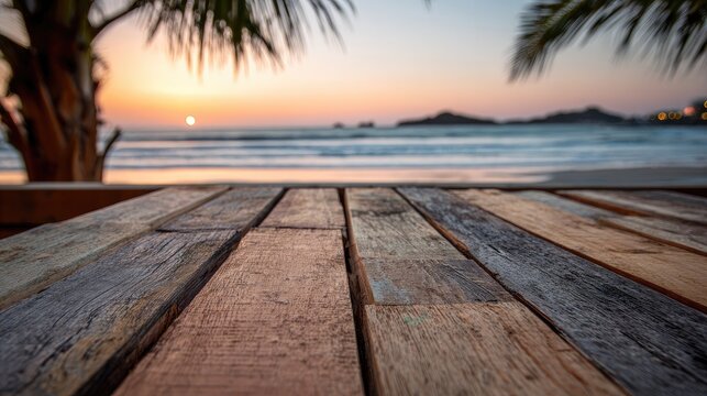 Weathered wooden table with a blurred ocean sunset and palm fronds