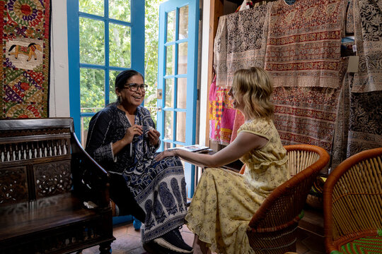 Women laughing in room with open window and tapestries