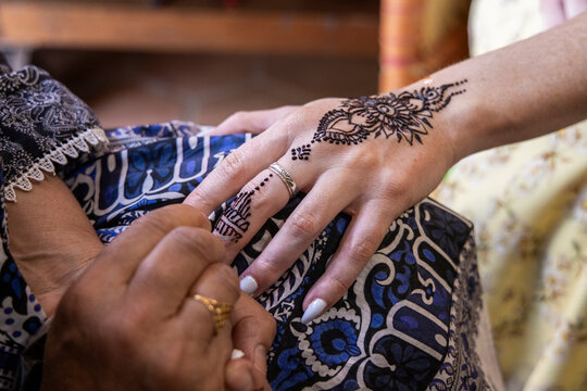 Woman getting henna body art applied to hand