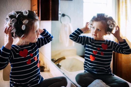 Young Girl Playing in Curlers in front of Mirror