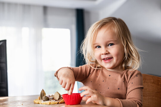 Blonde toddler girl smiling while playing at table