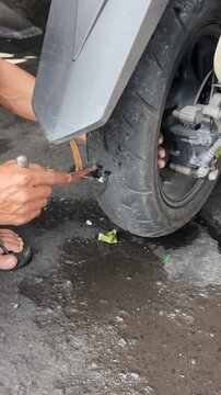 Mechanic Repairing Punctured Motorcycle Tire Using Tubeless Tire Plug Kit