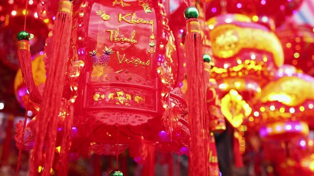 Traditional Vietnamese Tet holiday decoration close up. Red glowing lanterns with golden calligraphy text and lights at a festive street market during Lunar New Year in Nha Trang, Khanh Hoa, Vietnam.