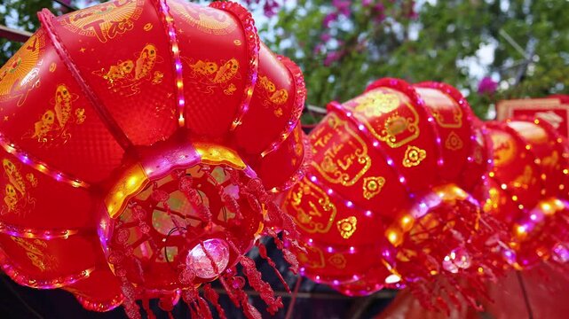 Traditional Vietnamese Tet holiday decoration close up. Red glowing lanterns with golden calligraphy text and lights at a festive street market during Lunar New Year in Nha Trang, Khanh Hoa, Vietnam.