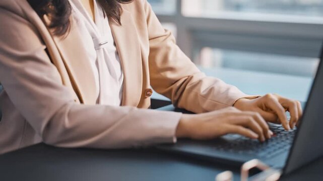Professional woman's hands typing on a laptop keyboard in a modern office, showcasing remote work, business communication, and digital productivity.