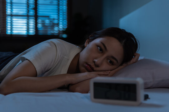 Young Asian woman suffer from insomnia can't sleep at night awaken from stress mental health problem or migraine. Young people health care psychiatry concept.