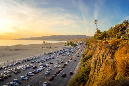 Santa Monica Beach in Los Angeles, California, at sunset, with Pacific coastline, traffic, and a lively tourist boardwalk atmosphere.
