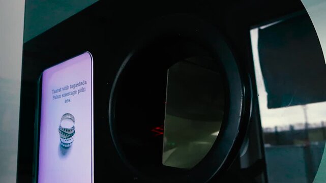 Person Returning Aluminum Cans to a Reverse Vending Machine for Recycling