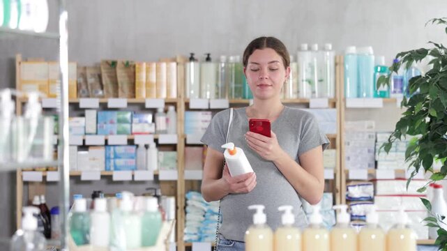 Happy pregnant woman customer holding, scan QR code on label and selecting cream or skin care product in modern drugstore 