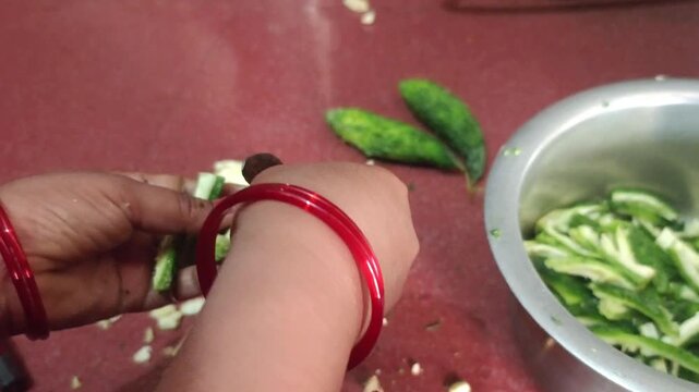 Woman hands cutting fresh bitter gourd with whole green karela and chopped slices on the side