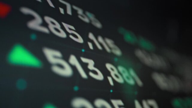 A finance professional sits before a monitor displaying dynamic stock market data. Instant updates on stock prices, currencies, and indices flash on screen, offering investors crucial insights