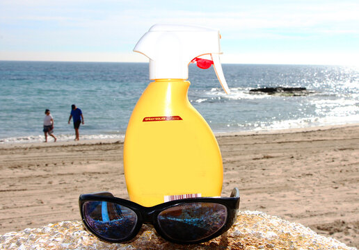 Crema de sol protector solar, playa y bronceado piel rayos UVA , gafas de sol y mar de fondo en verano con olas, horizonte y brillo reflejo 