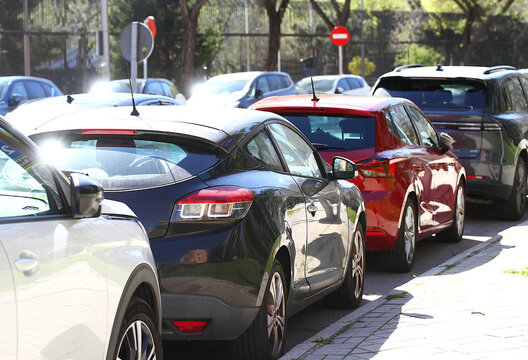 Coches aparcados en fila estacionados en calle de ciudad acera v&iacute;a p&uacute;blica