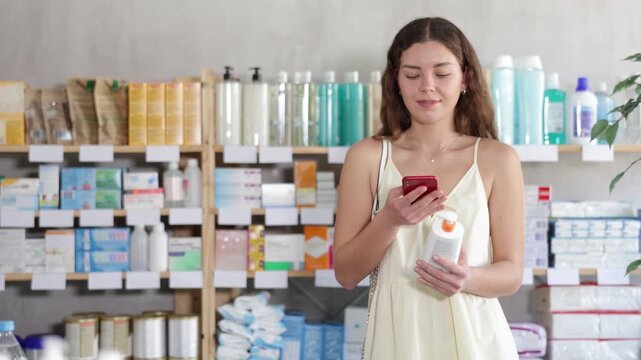 Young woman scans barcode a package of stretch marks and cellulite cream on her mobile. Buyer pays for purchases in the pharmacy using an online application. High quality 4k footage