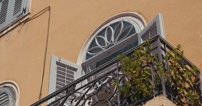 Arched window with open shutters and balcony railing on a building facade on Sergius Street.