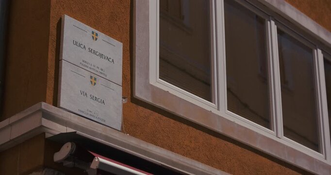 Street name sign for Sergius Street mounted on a building facade beside a window.