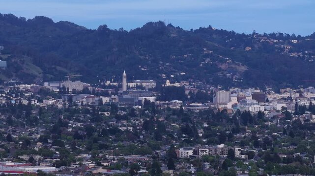 Evening aerial view of Berkeley, California, showing the city skyline against the rolling hills and the prominent Sather Tower (Campanile) of the University of California campus