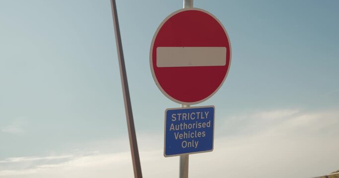 Slow motion shot of a no entry sign with authorised vehicles only text against the sky