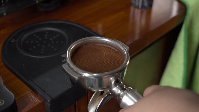 A bartender using Tamping coffee ground in porta filter to extract coffee