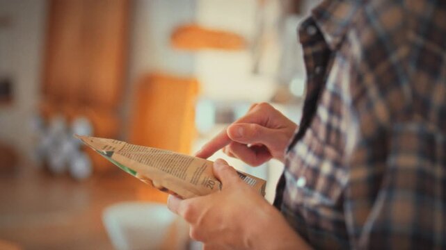 A girl meticulously reads the ingredients on a product's plastic packaging in a sunlit kitchen, scanning for harmful additives. Her careful check underscores proper nutrition and food quality control