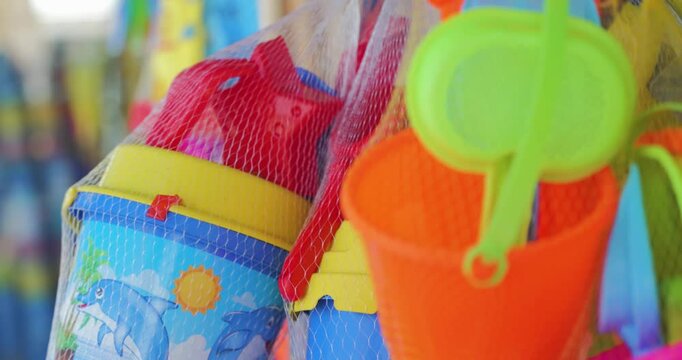 Slow motion, close-up shot of colourful buckets spades and toys hanging outside a seaside shop