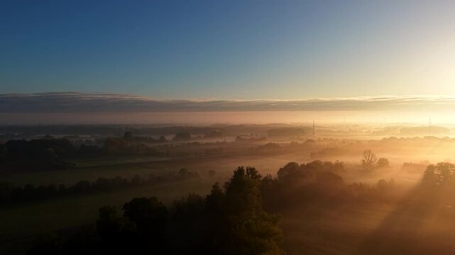 Golden sunrise with misty fields and farmland landscape in America. Aerial dolly forward wide shot. Quiet and peaceful rural suburb area. Majestic nature scenery in USA. Panorama view.