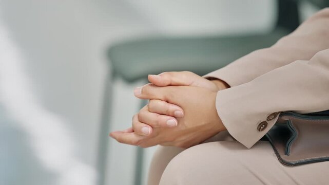 Close-up of a person's clasped hands, reflecting patience, contemplation, or anxiety in a professional setting. Ideal for themes of waiting, job interviews, business meetings, or thoughtful moments.