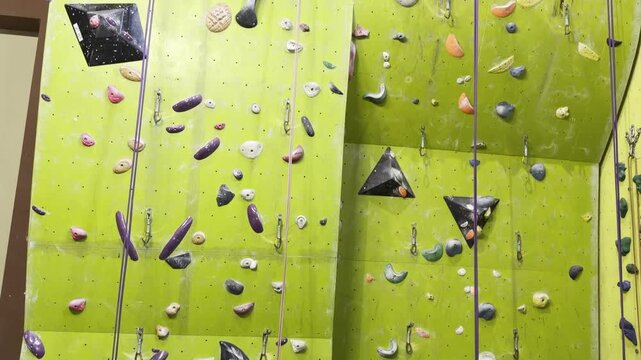 Indoor rock climbing wall with colorful holds and ropes