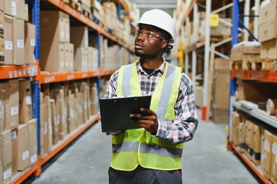 African american warehouseman with clipboard checking delivery, stock in warehouse
