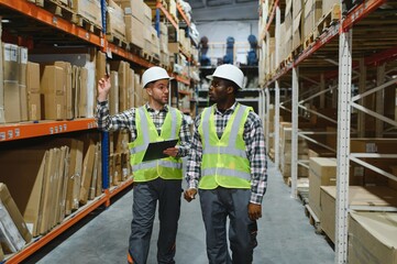 Fototapeta premium Two professional warehouse workers stand between shelves of products