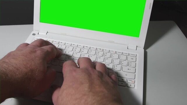 Green screen background with hands typing on a laptop in a bright indoor setting