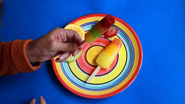 Comer y chupar helado polo fruta color palito de madera y espiral hielo paleta pirulo ice cream y plato multicolor con fondo azul blue background en verano refrescante summer fresh