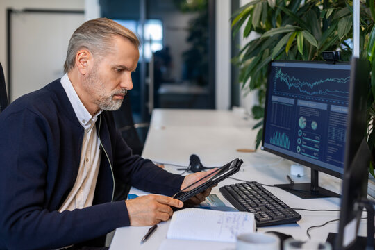 Handsome mature businessman manager sitting in office with tablet computer